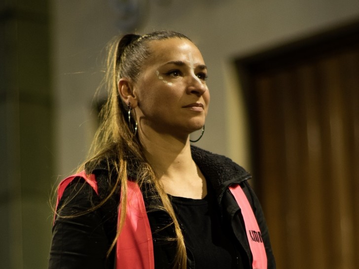 Anna Levin with her hair in a ponytail wearing a hi-vis jacket holds a camera