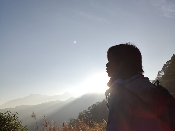 Wendi Sia photographed from behind, looking over a mountainous landscape.