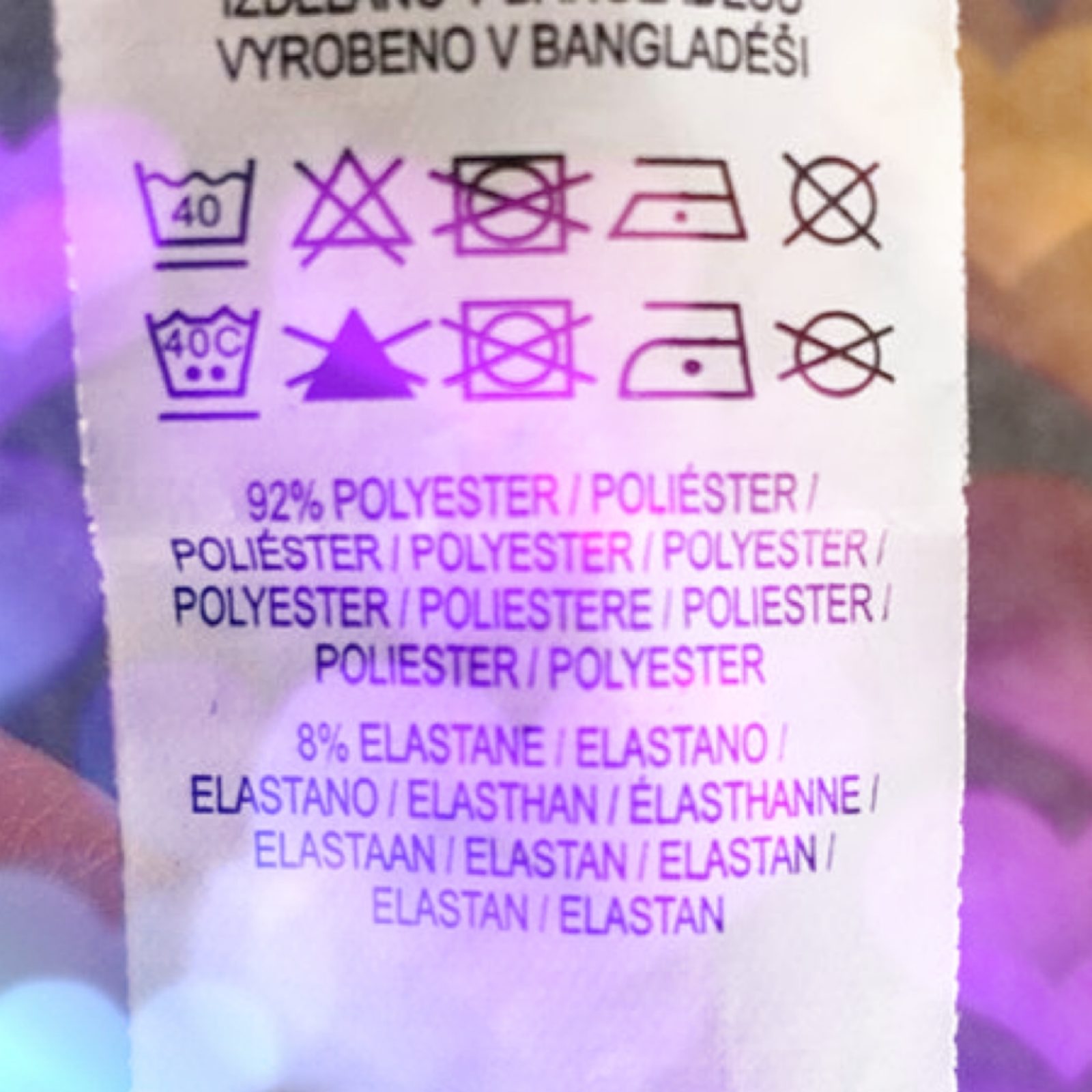 Photo os washing instructions on a clothes label with a violet sparkly pattern overlayed on top.