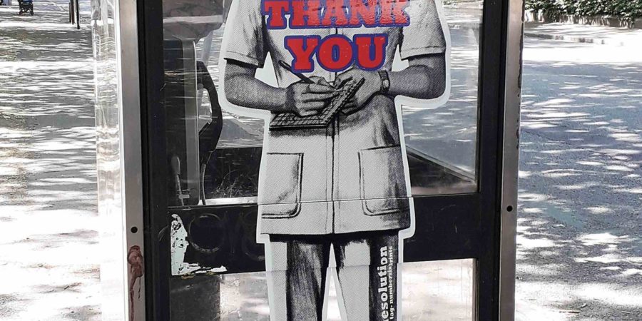 On the side of a phone box a black and shite image of a nurse covers the full height of the window with the words 'NHS Careers Thank You.'