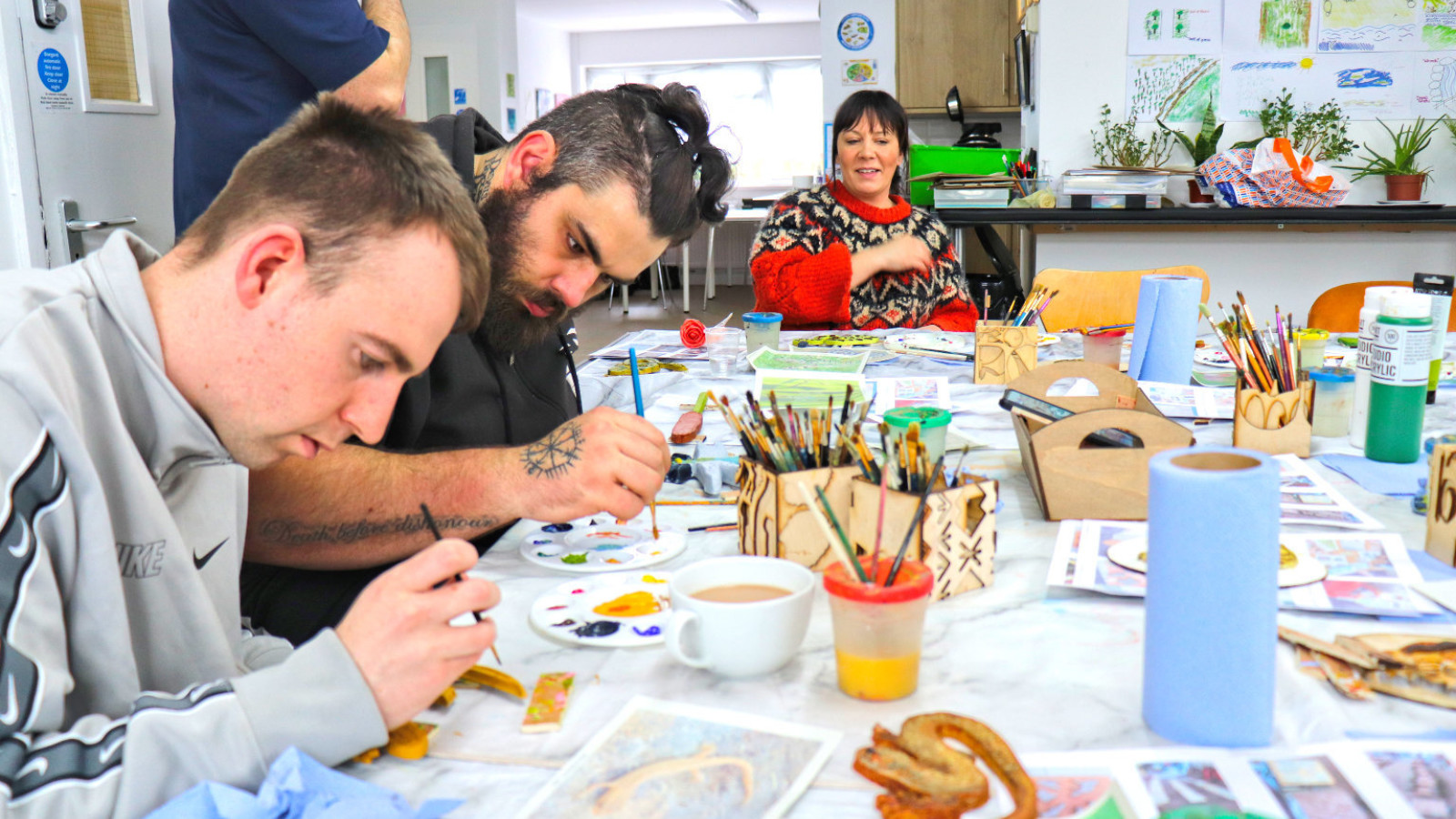 A group of adults sit around a table painting small clay objects