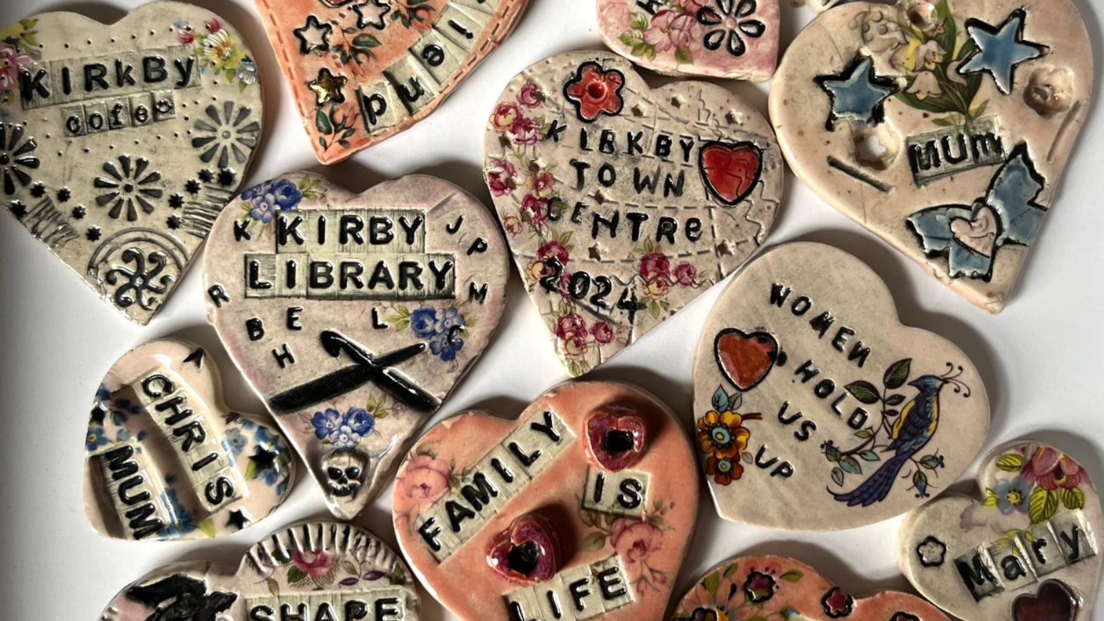 Photograph of a collection of clay hearts, each inscribed with a woman's name