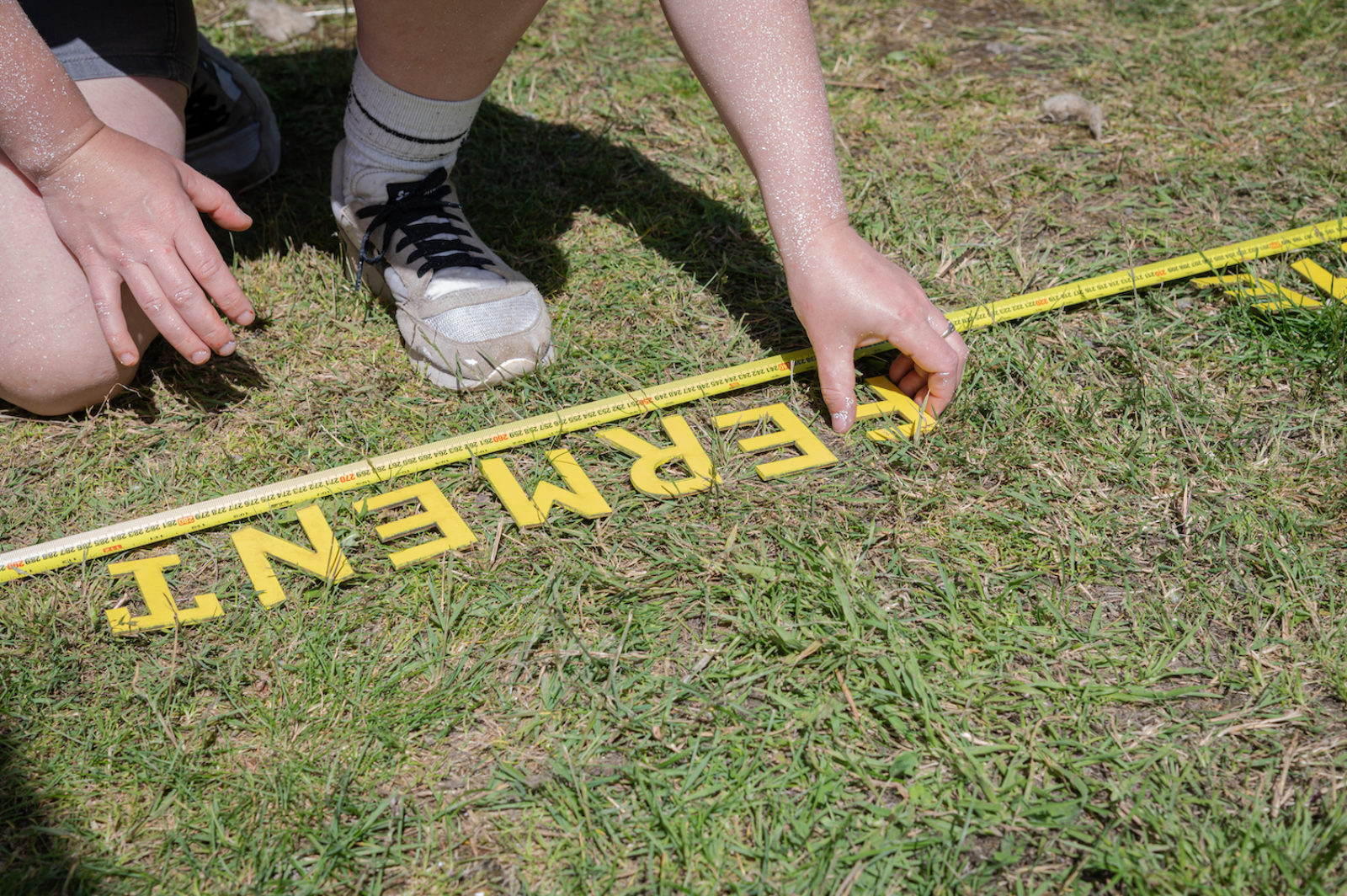 Photograph of an adult laying out wooden letters on the grass t o spell "ferment"