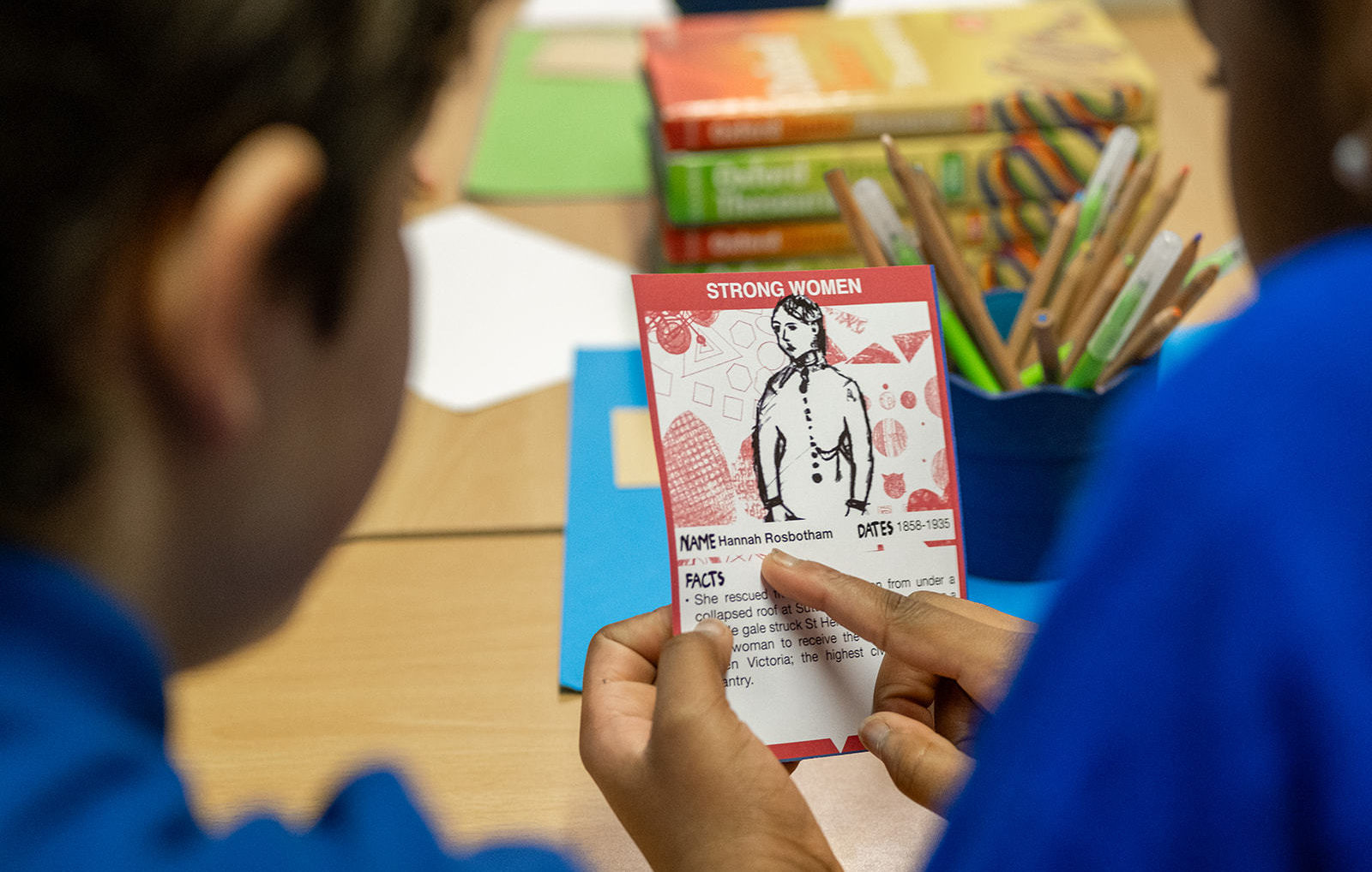 2 kids look at the resource and point at a card.