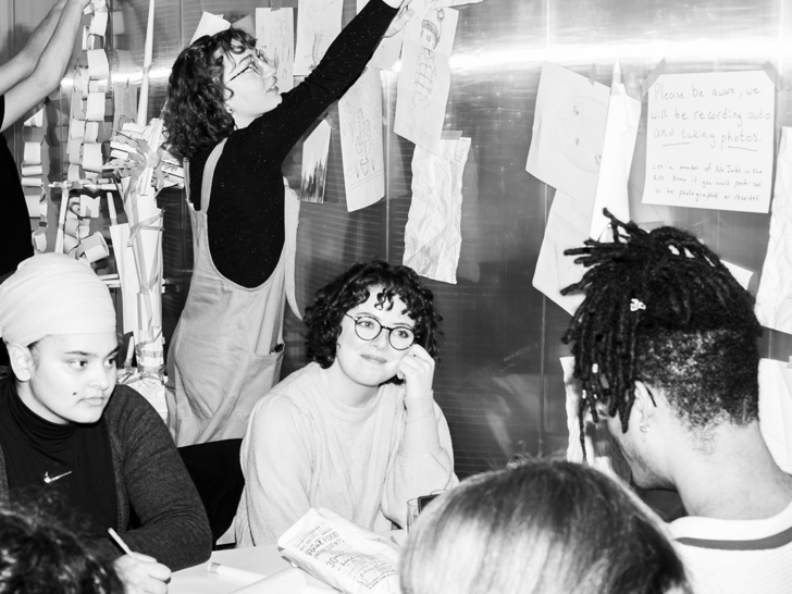 Photograph of a group of young professionals talking and making notes